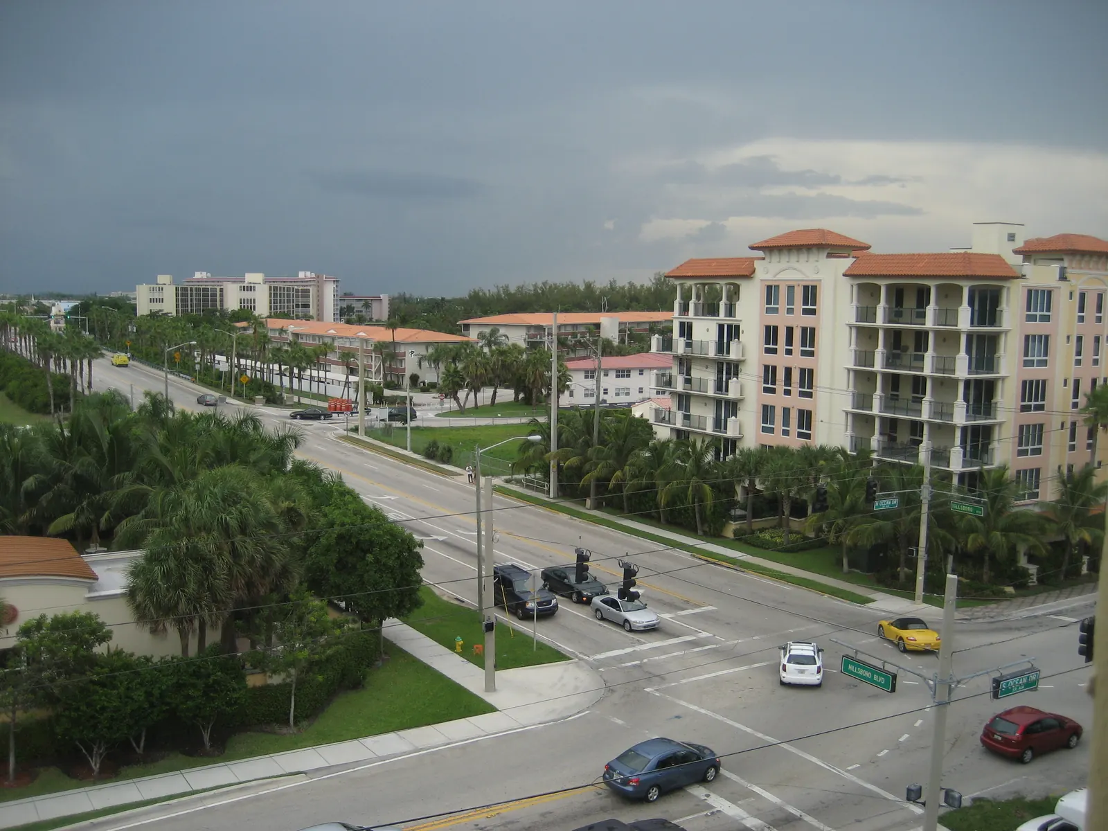 Traffic at the intersection of Hillsboro Boulevard and A1A in Deerfield Beach, seen from above, with palms and mid-rise buildings.