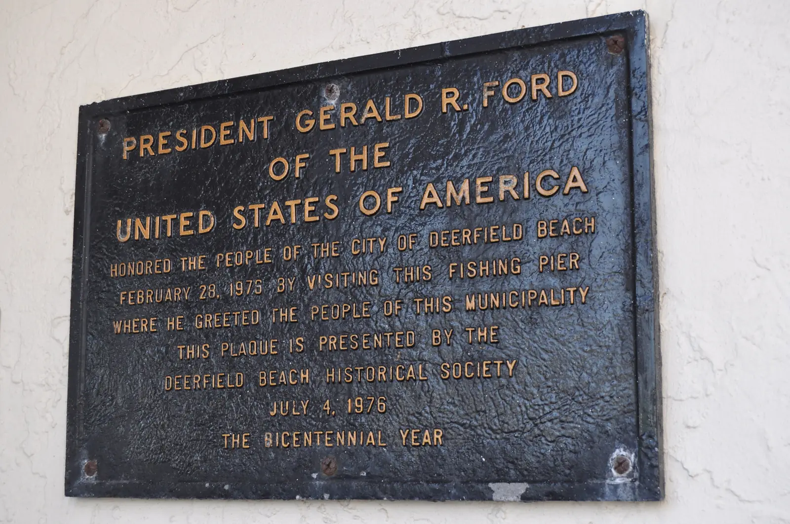 A bronze plaque at the pier entrance from the Deerfield Beach Historical Society recording that President Gerald R. Ford visited the fishing pier on February 28, 1975.