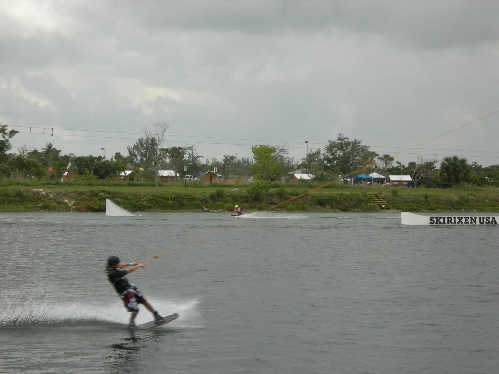 A rider on a wakeboard pulled by the overhead cable across the lake at Quiet Waters Park.